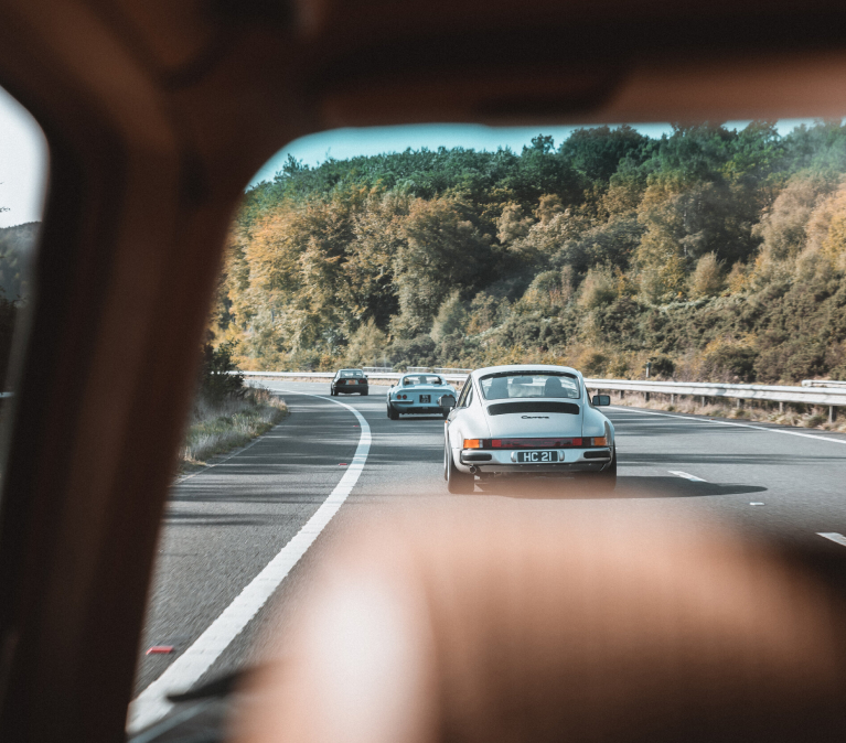 View from one classic car window looking at a classic porsche driving