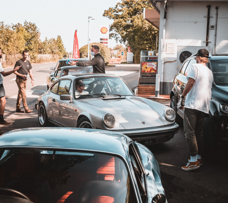 Group of classic cars and drivers at a petrol station