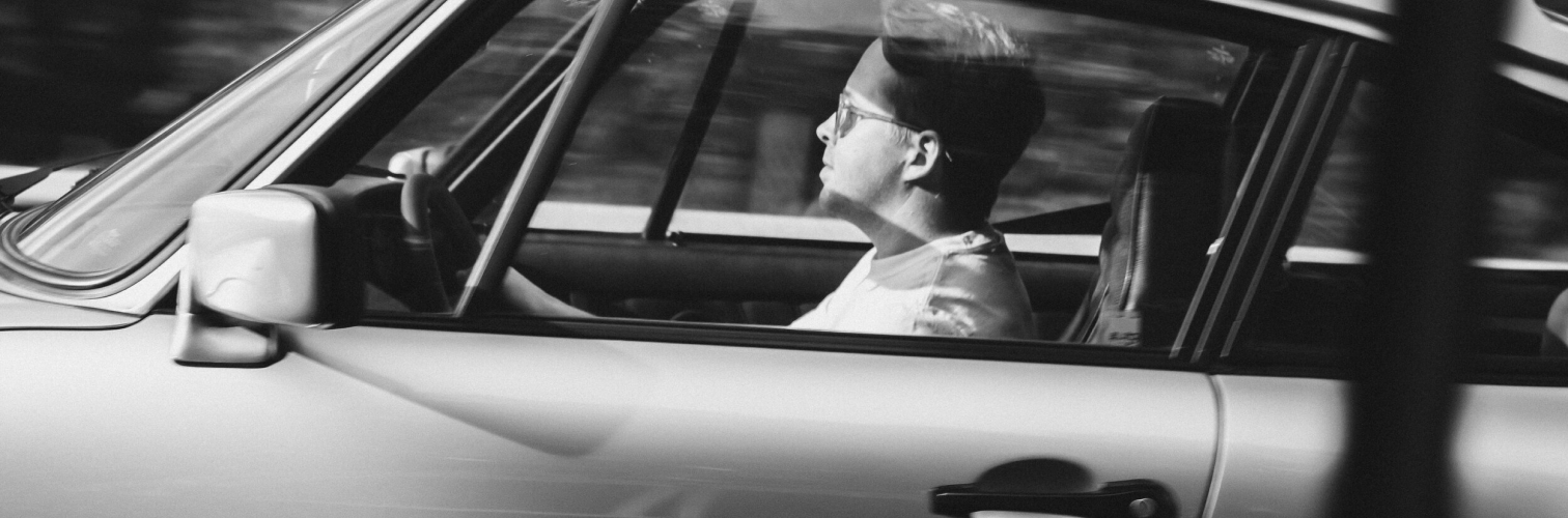  A man is driving a car with a black and white interior.