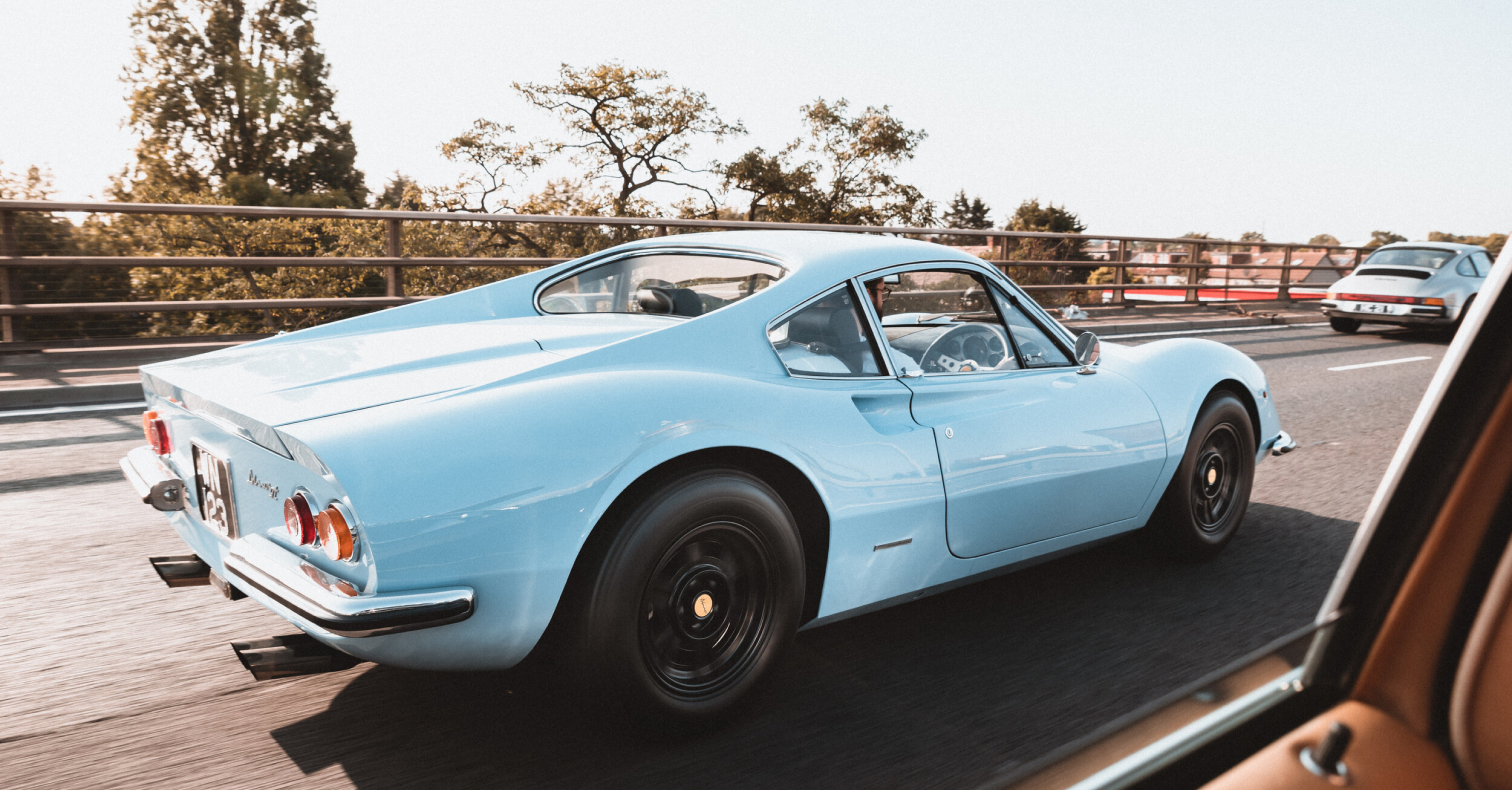 A blue sports car is driving on a highway.