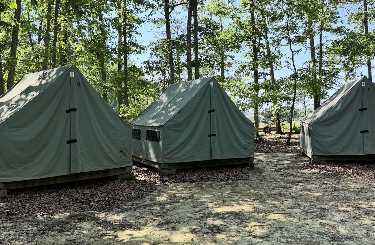 A camping site with a fire going and smoke rising. In the background is a picnic table.