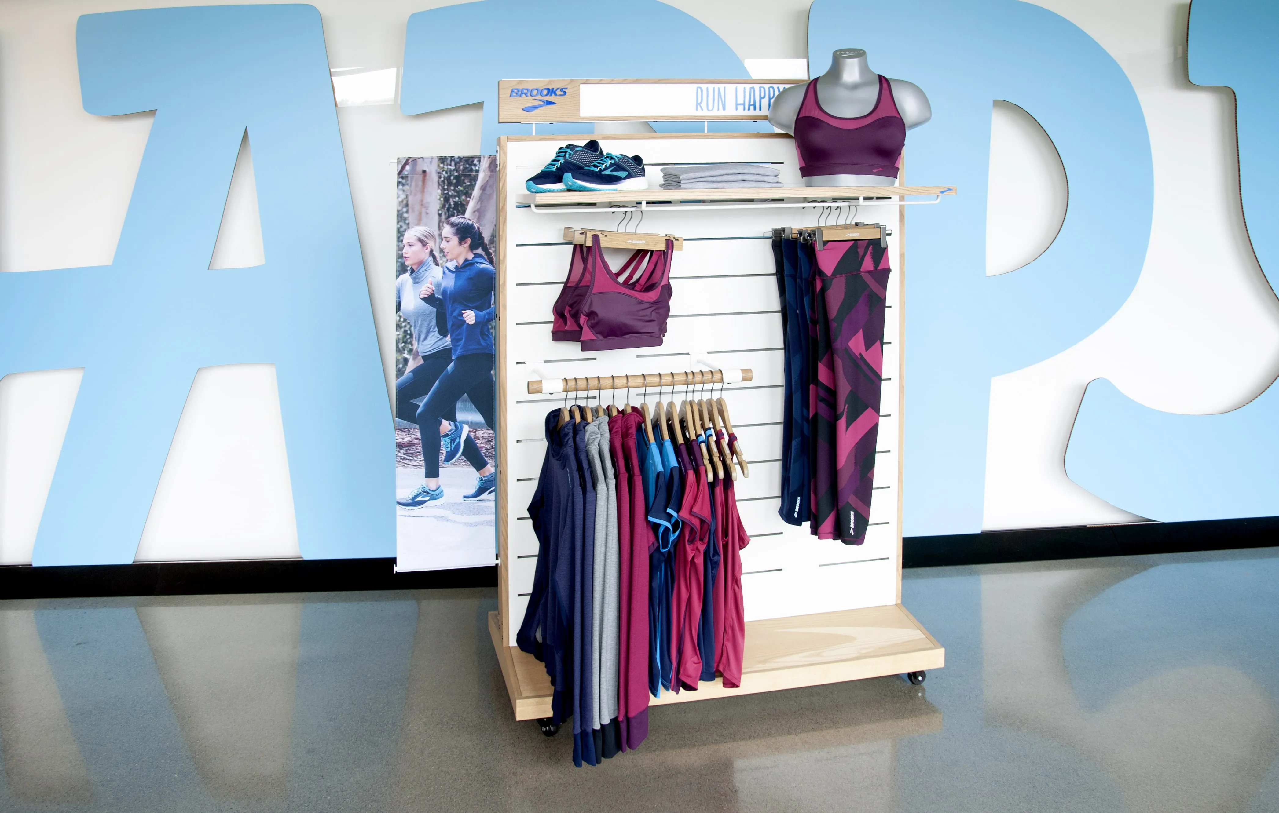 Brooks athletic apparel retail display with custom white slatwall fixtures, sports merchandise, and product showcasing