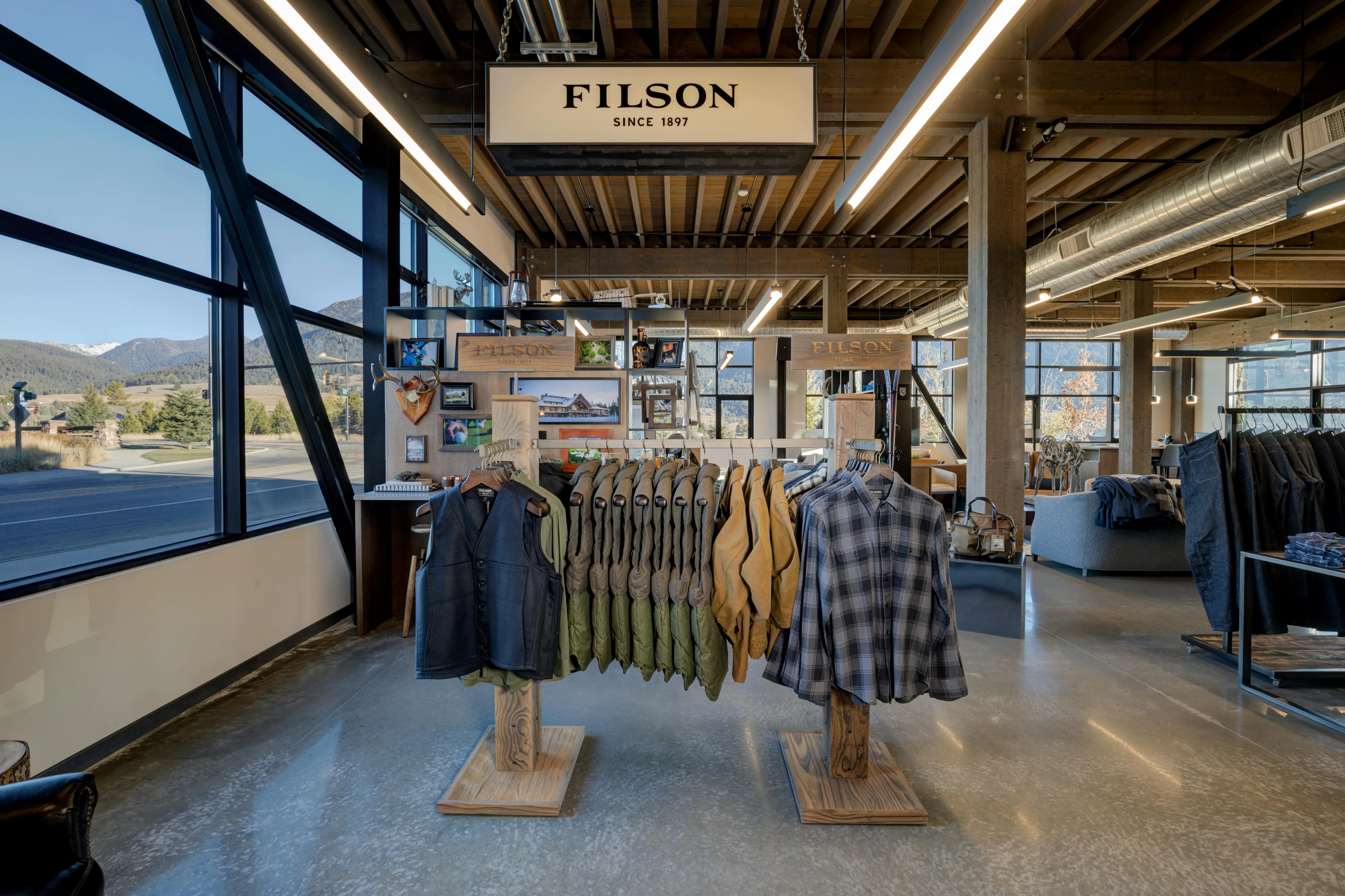 Filson retail store with custom wooden clothing stands, metal shelving, apparel displays, and industrial ceiling design