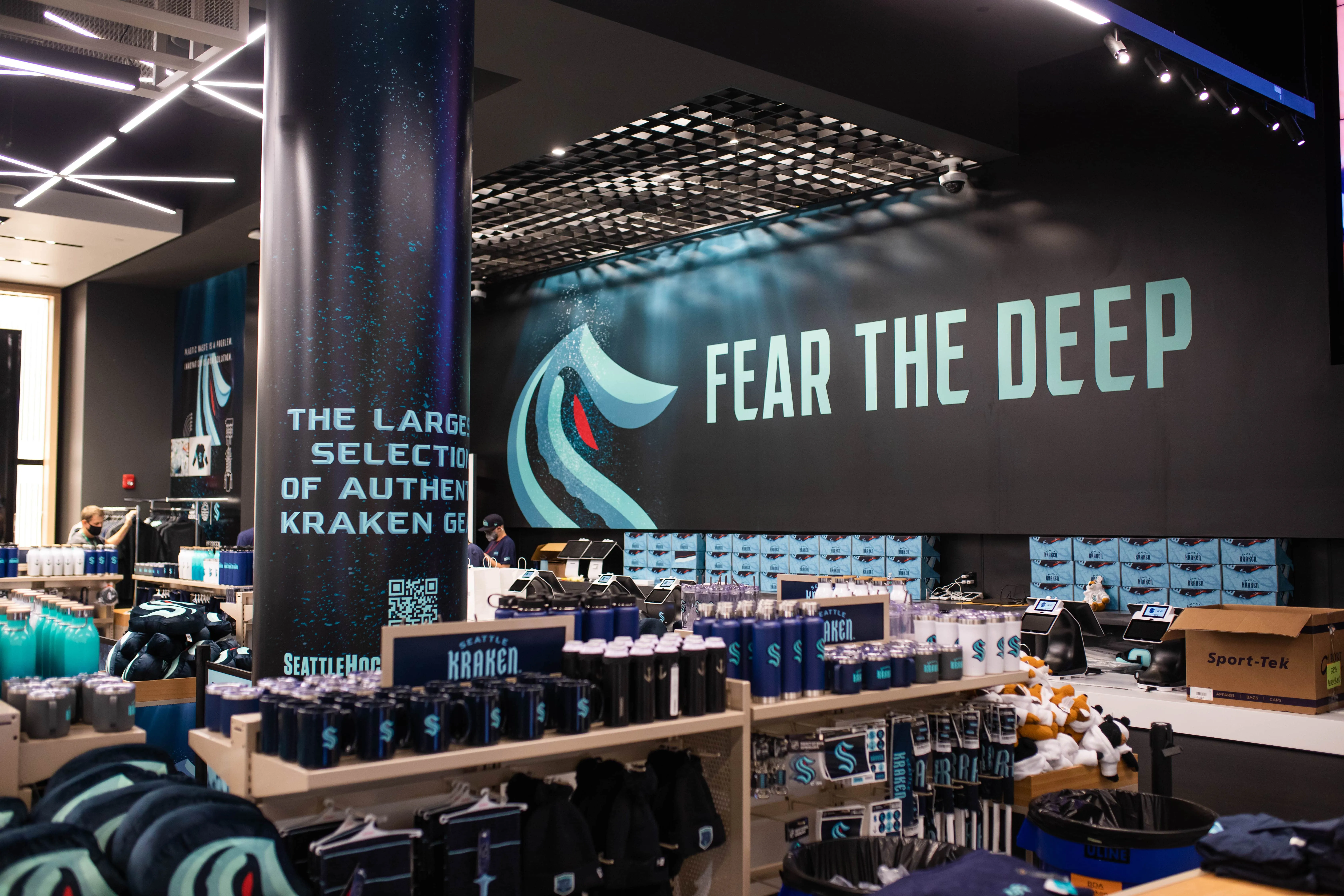 Seattle Kraken NHL team retail store interior with 'Fear The Deep' branded signage, apparel displays, merchandise shelving, and team merchandise