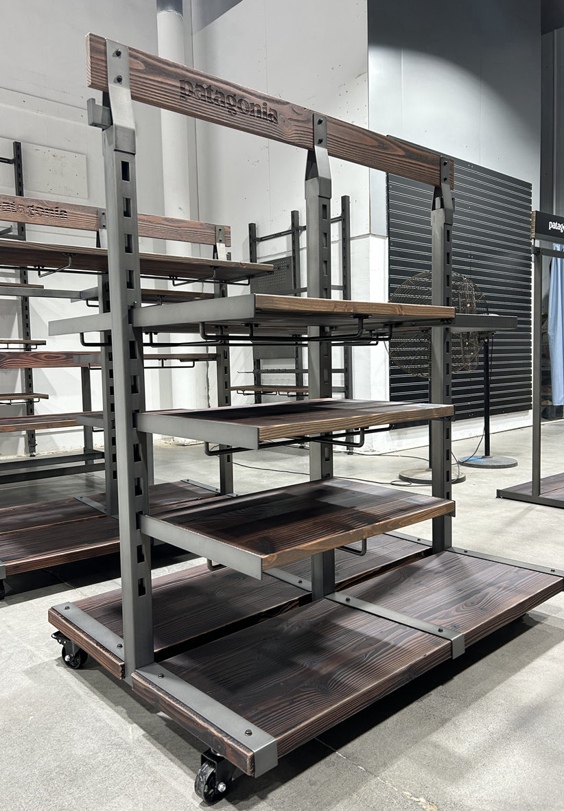 Custom Patagonia retail fixture with metal frame structure, steel stairs, and industrial shelving during assembly in manufacturing facility