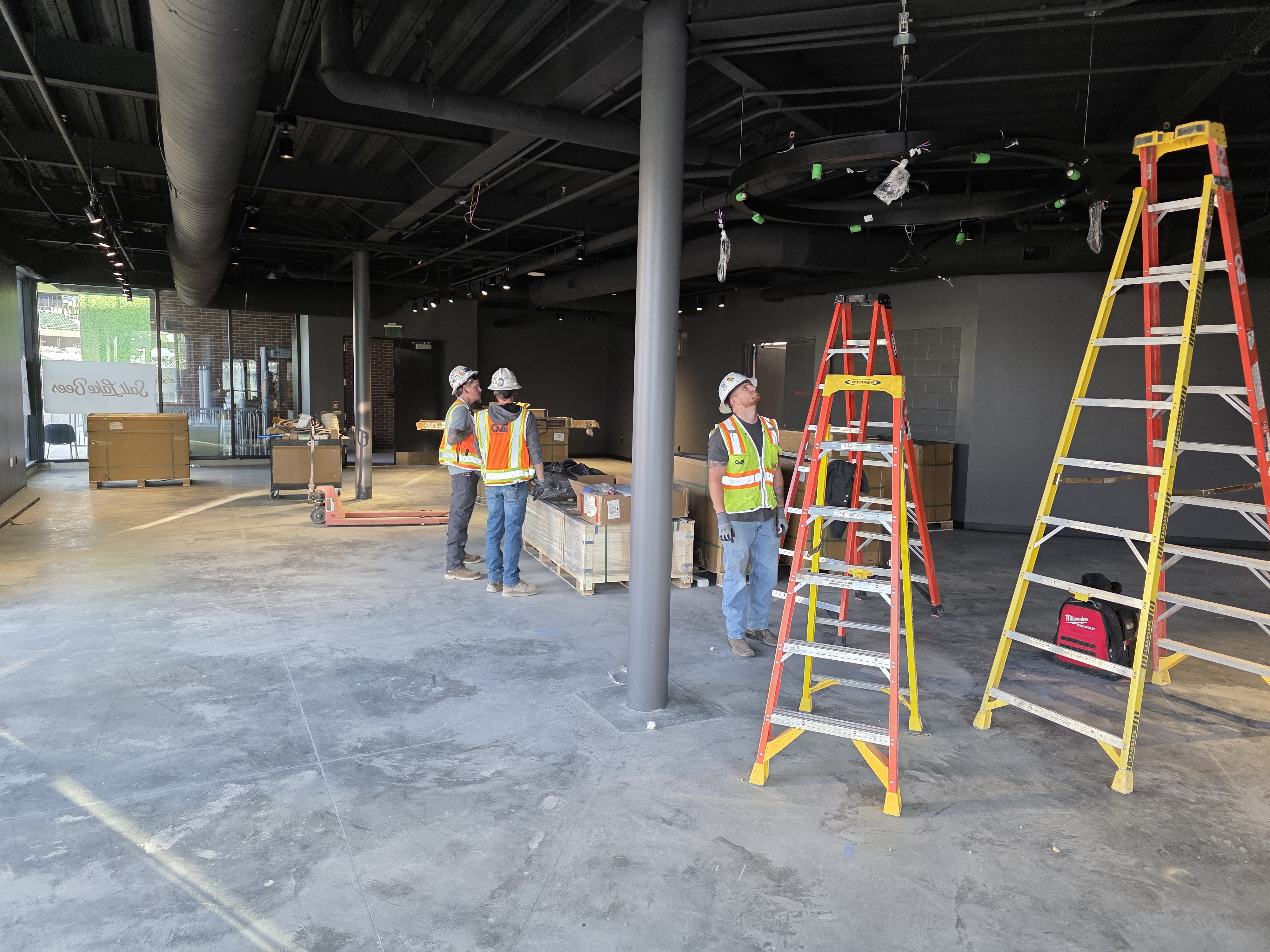 Seattle Kraken team store installation at Climate Pledge Arena with installation crew, scaffolding, and buildout in progress