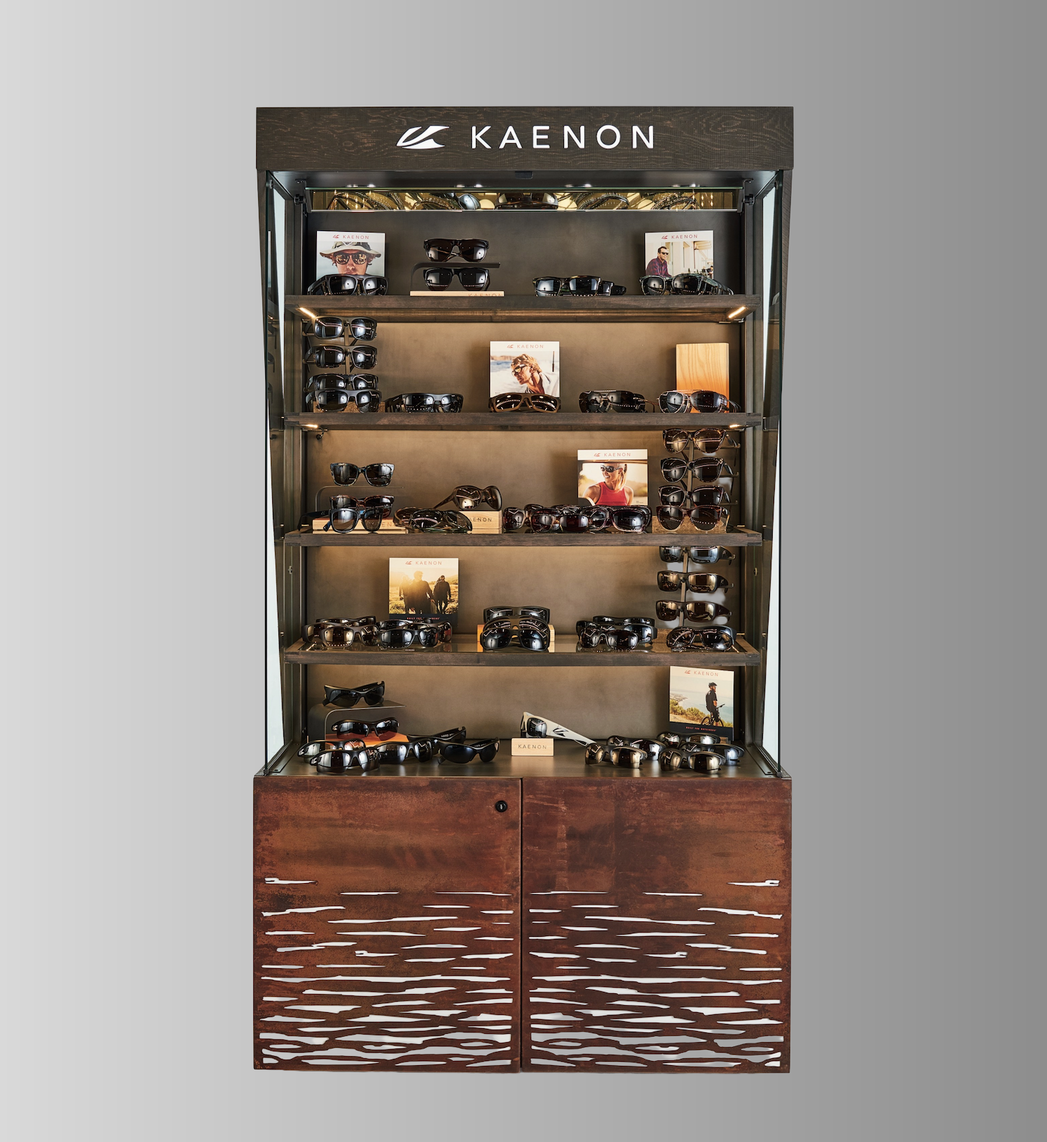 Kaenon eyewear retail display case with tiered shelving, illuminated backdrop, wood base with textured doors, and product photography displays