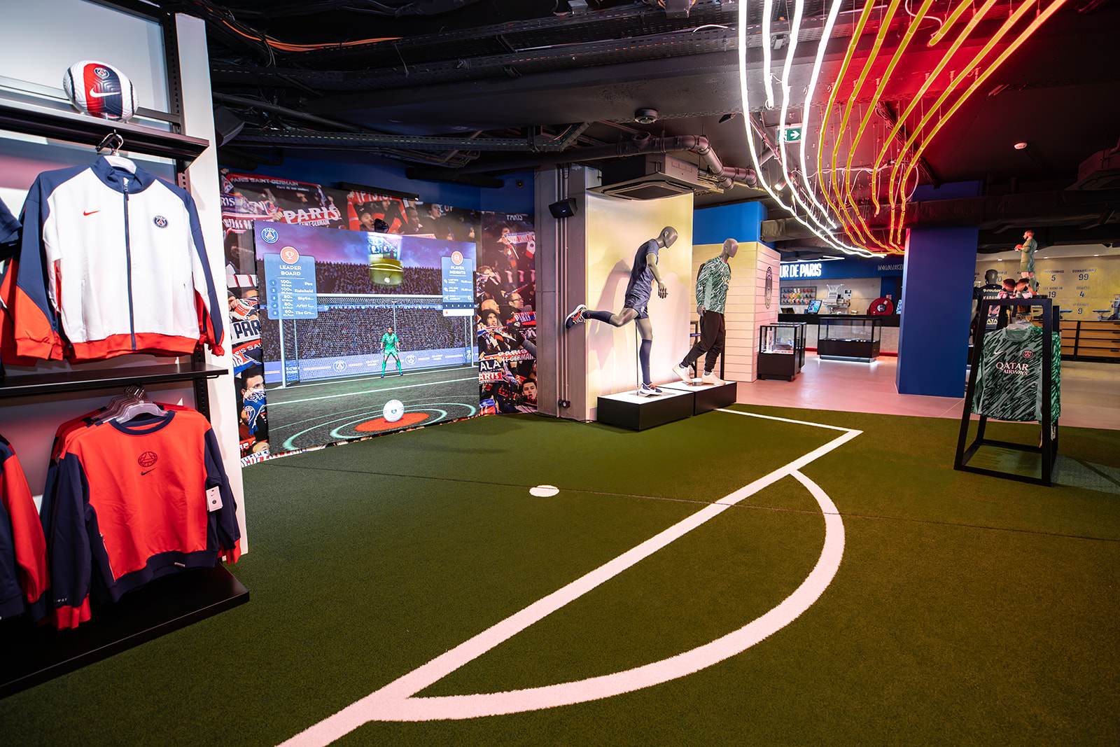 Paris Saint-Germain PSG retail experiential space with soccer field turf, interactive displays, branded signage, and neon accents