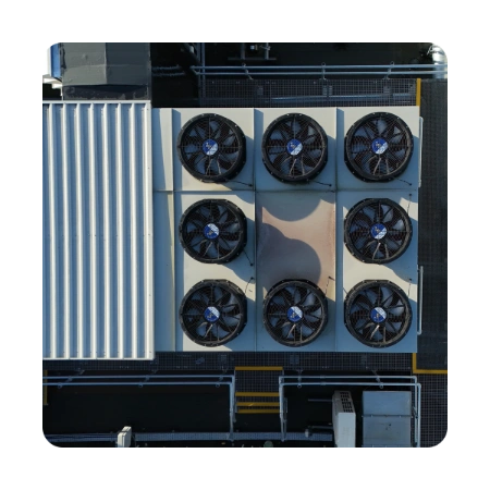 Top down aerial view of a large, traditional industrial rooftop air cooling unit equipped with eight heavy duty exhaust fans.