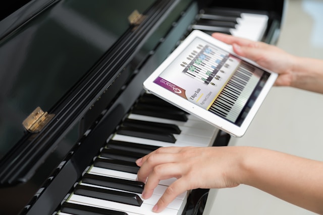 Person using a piano learning app on a tablet while practicing piano