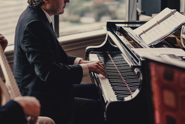 Person reading sheet music while playing the piano.