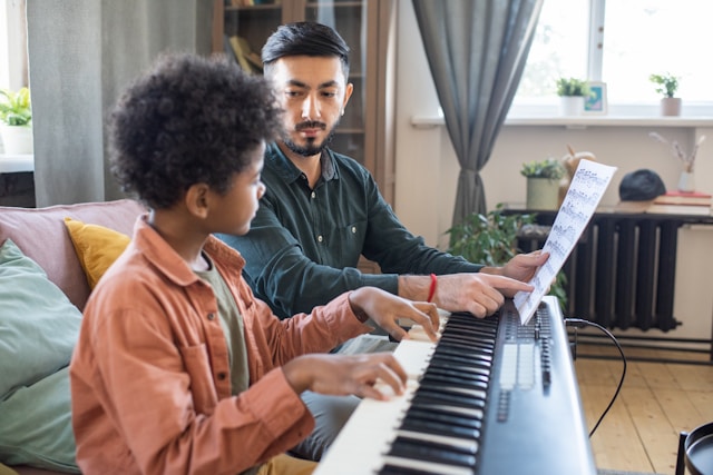 Piano teacher guiding a student during a piano lesson