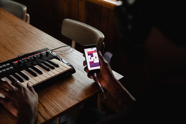 Person practicing piano with a smartphone learning app and MIDI keyboard