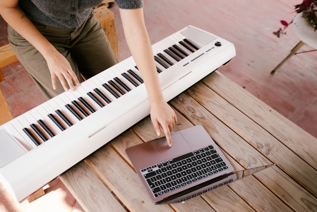 Person practicing piano with real-time feedback displayed on a laptop