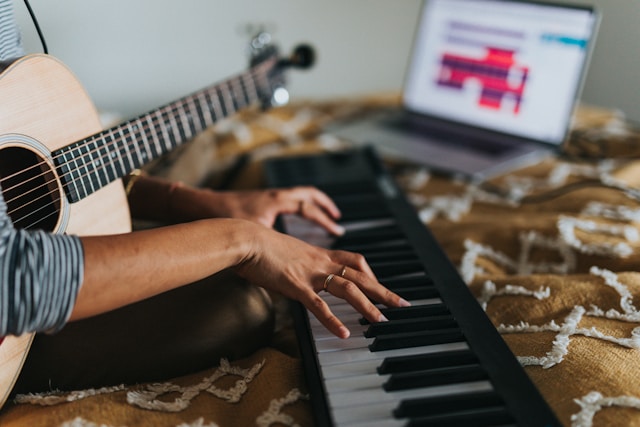 Adult learning piano on a MIDI keyboard with a laptop.