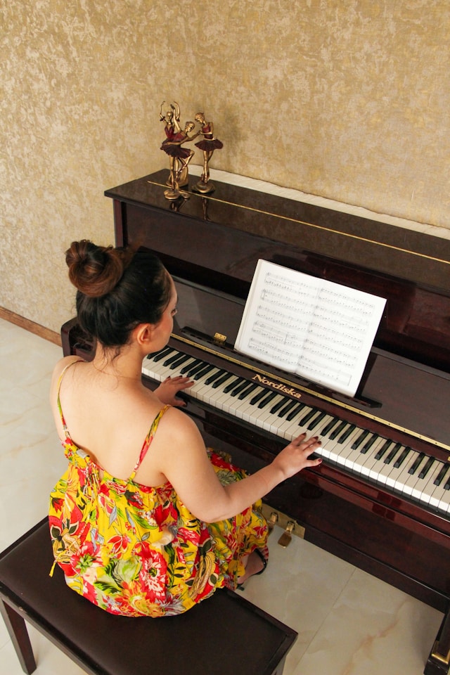 Adult piano learner pausing during practice to reflect on mistakes while reading sheet music.