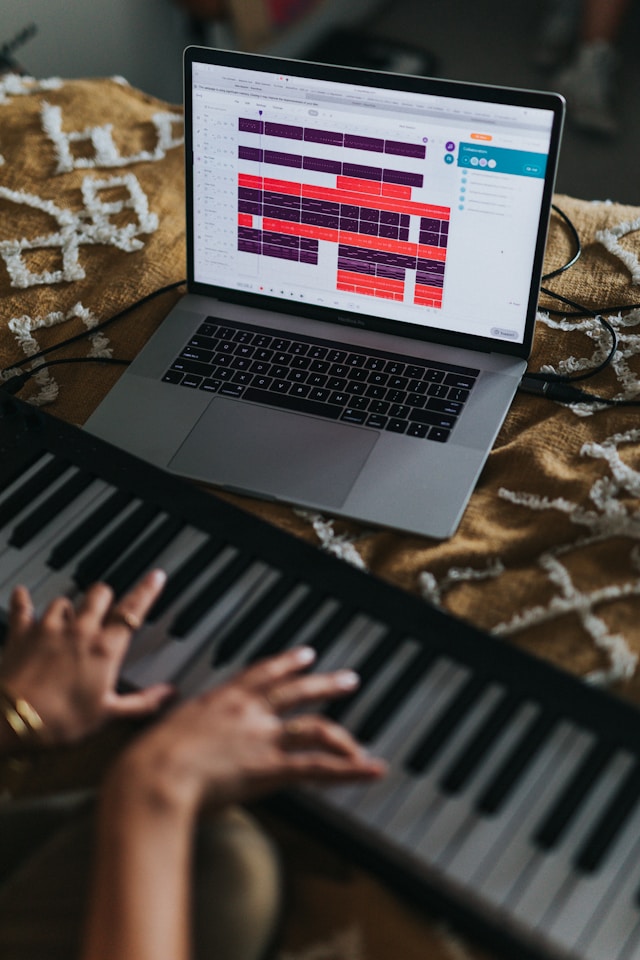 Adult practicing piano at home using a digital keyboard and learning software.