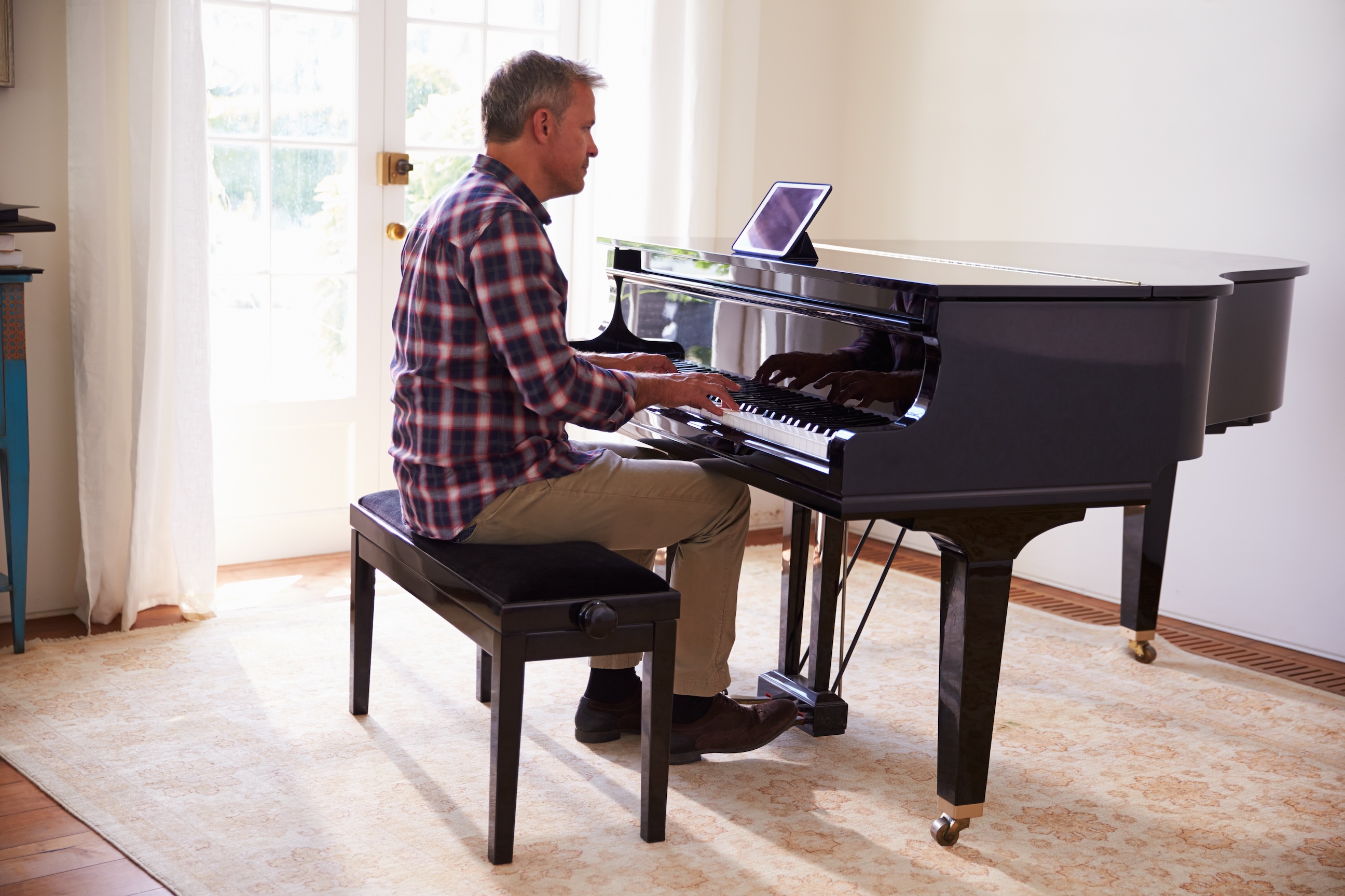 Adult practicing on a digital piano with interactive learning tools at home.