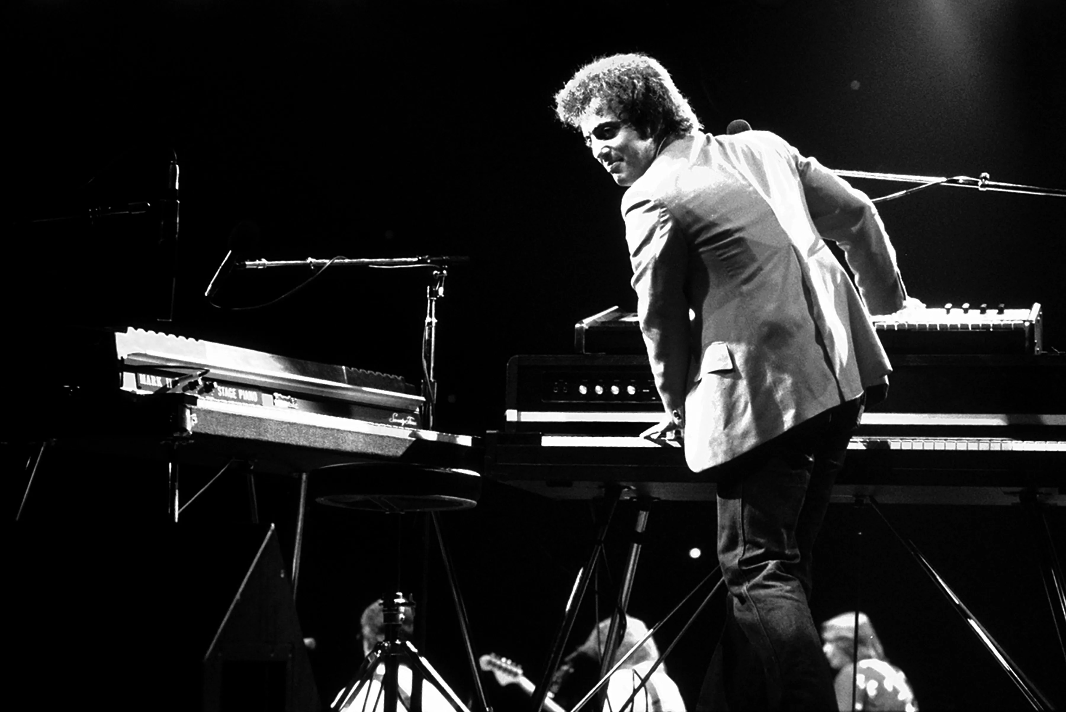 Billy Joel on stage with multiple keyboards.