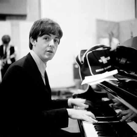 Paul McCartney at the piano looking into the camera.