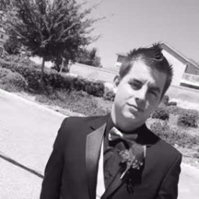 A black and white photograph of Nikolai Annennkoff standing with a serious face in what looks like a prom photo. 😂