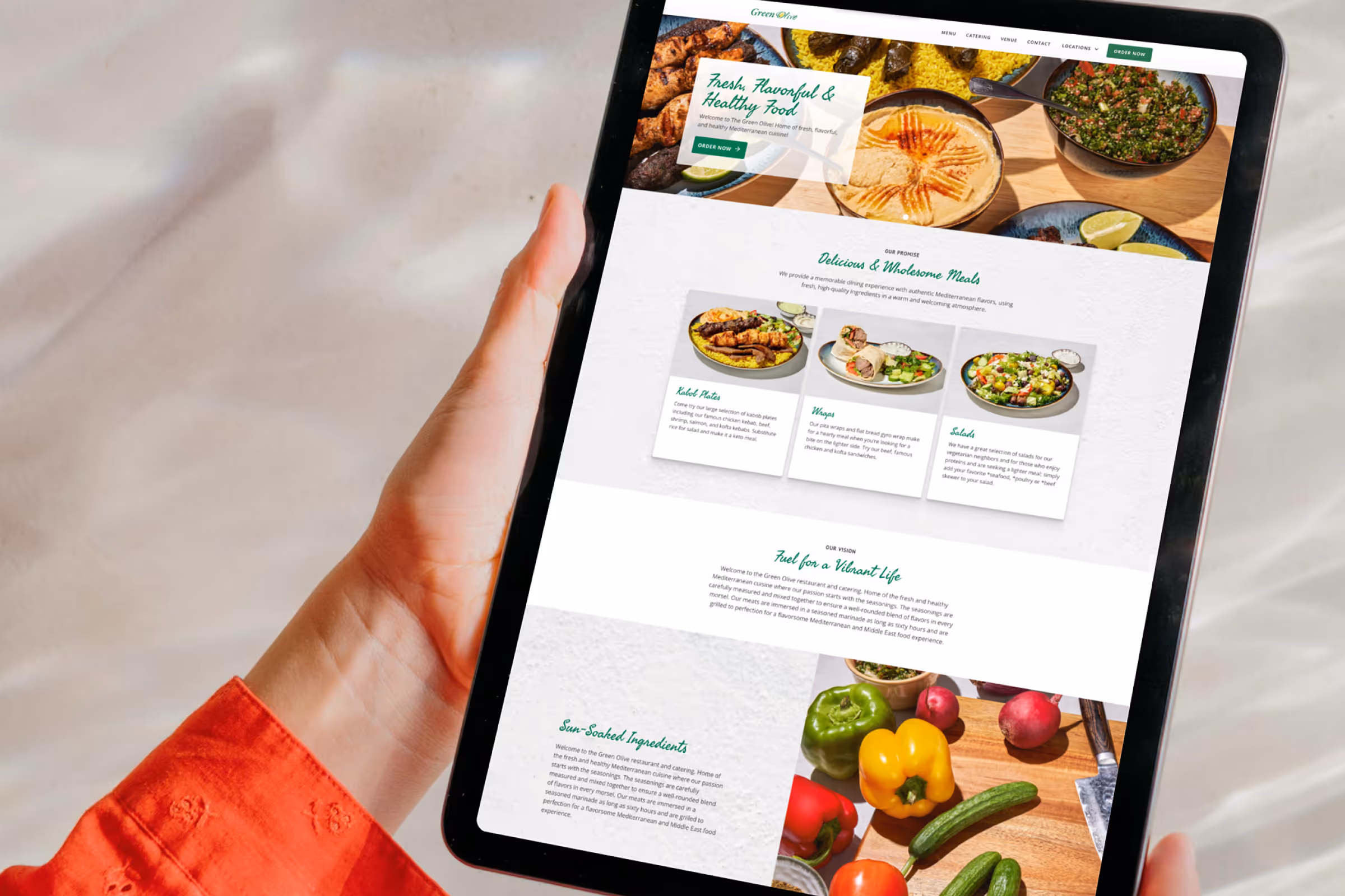Person viewing The Green Olive Catering website on a tablet.