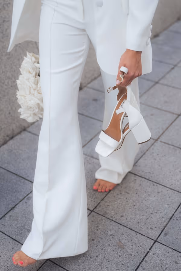 Braut trägt ihre High Heels in der Hand.