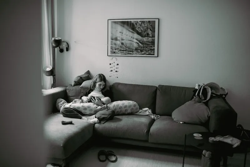 Eine stillende Mutter auf dem Sofa in einer schwarz-weiß Foto Aufnahme.