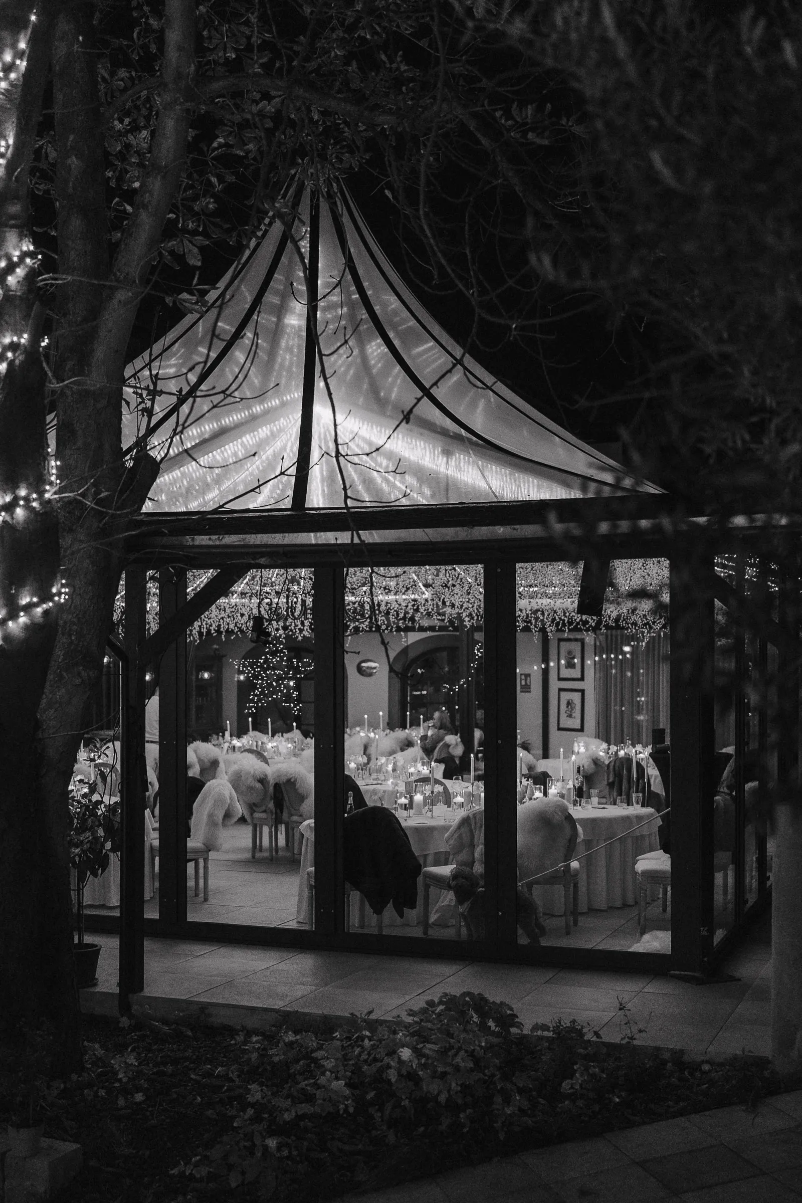 Abendaufnahme eines festlich dekorierten Pavillons im Morrhof mit gedeckten Tischen und Lichterketten.