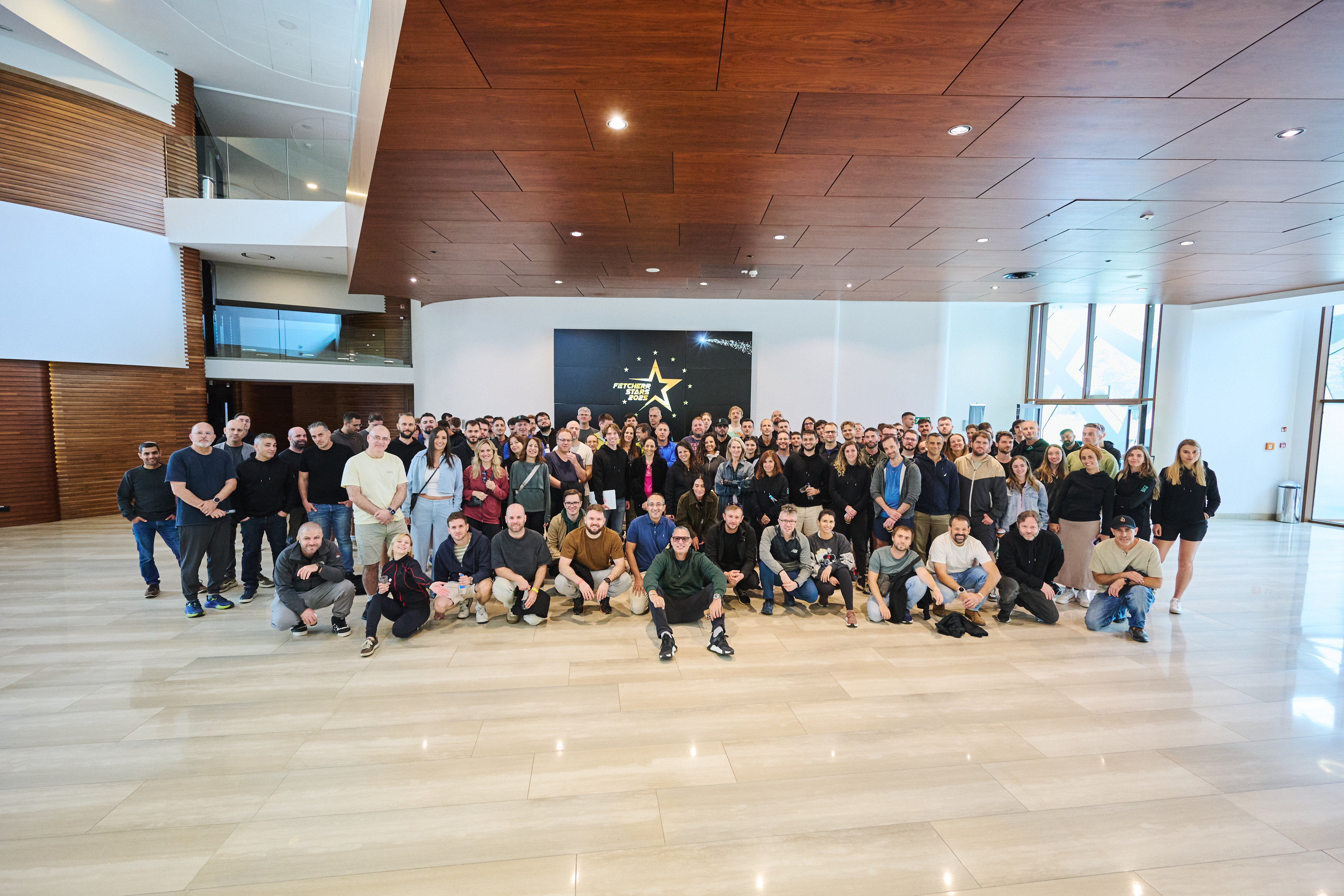 Group photo of the Fetcherr team gathered in a modern office lobby during a company event