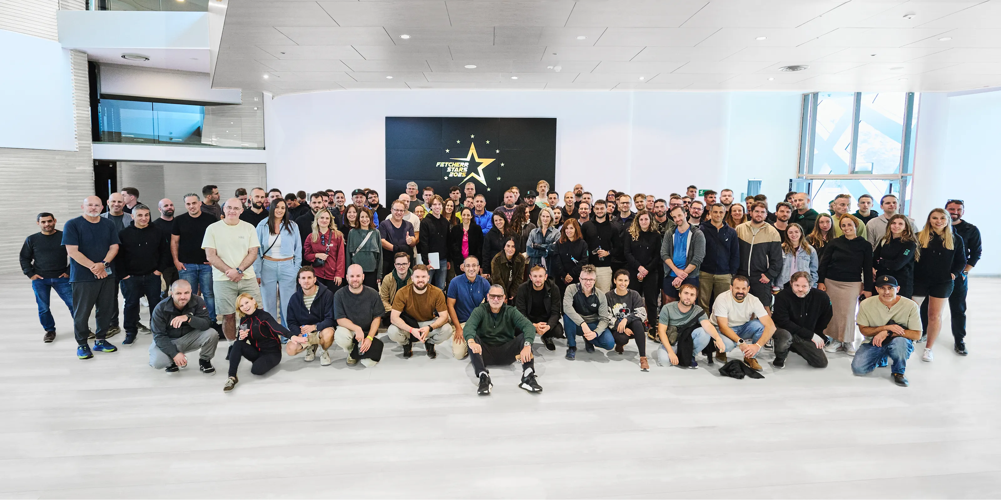 Group photo of the Fetcherr team gathered in a modern office lobby during a company event