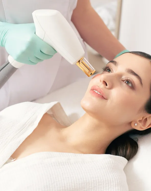 Woman receiving facial treatment with a handheld device operated by a gloved professional.