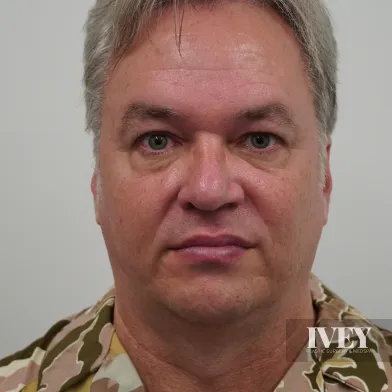 Middle-aged man with gray hair wearing a camouflage-patterned shirt against a plain background.