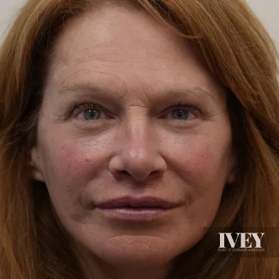 Close-up of a middle-aged woman with light skin, green eyes, and reddish-brown hair looking straight at the camera.