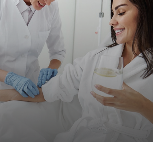 Healthcare professional in gloves administering an injection to a smiling woman holding a glass of water.