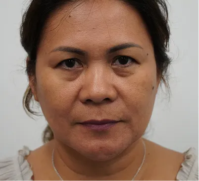 Close-up of a woman with short dark hair and neutral expression against a plain background.