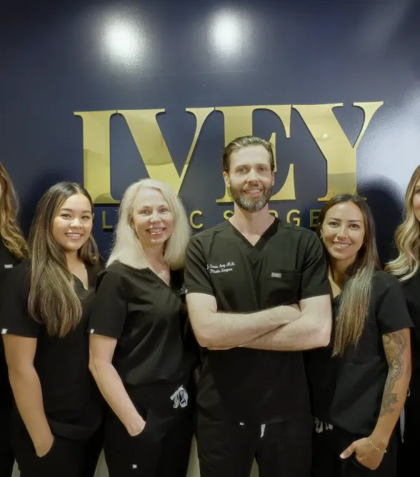 Five medical professionals in black scrubs standing in front of a gold IVFY logo on a dark wall.