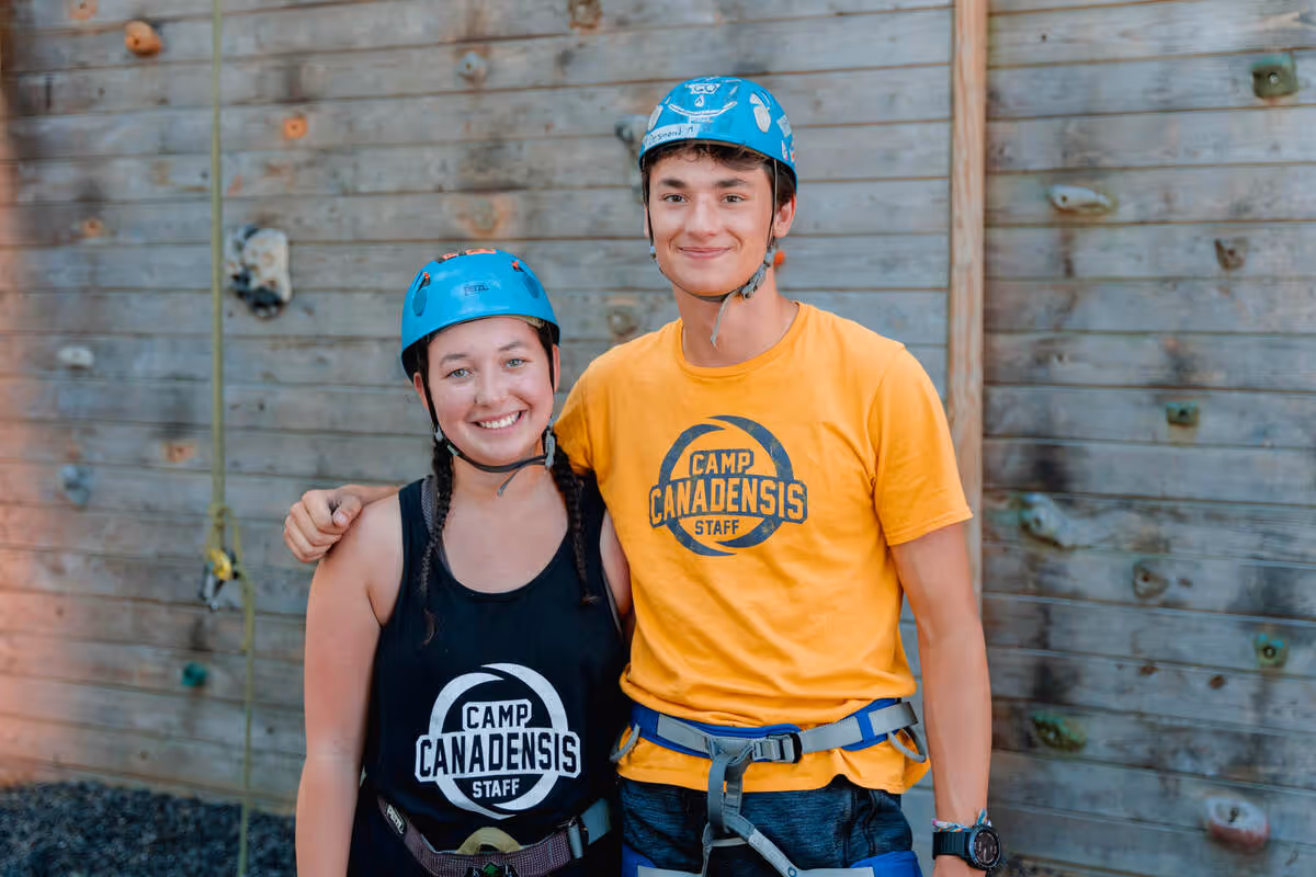 Two summer camp staff working at a rock climbing wall.