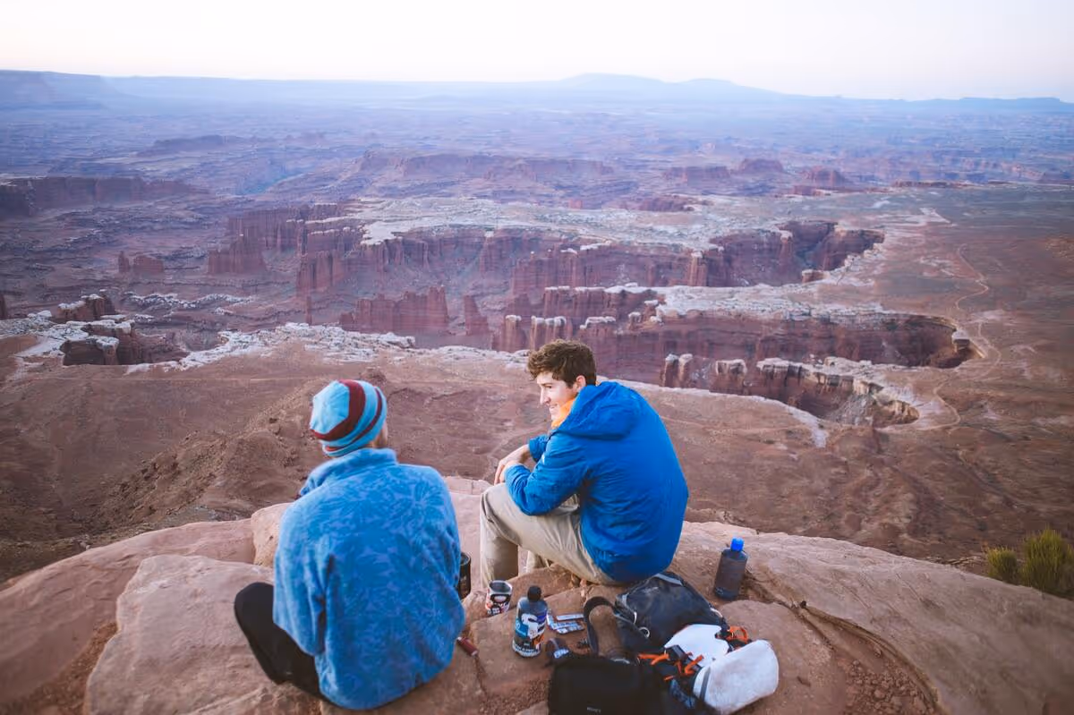Two friends chatting on the edge of a canyon.
