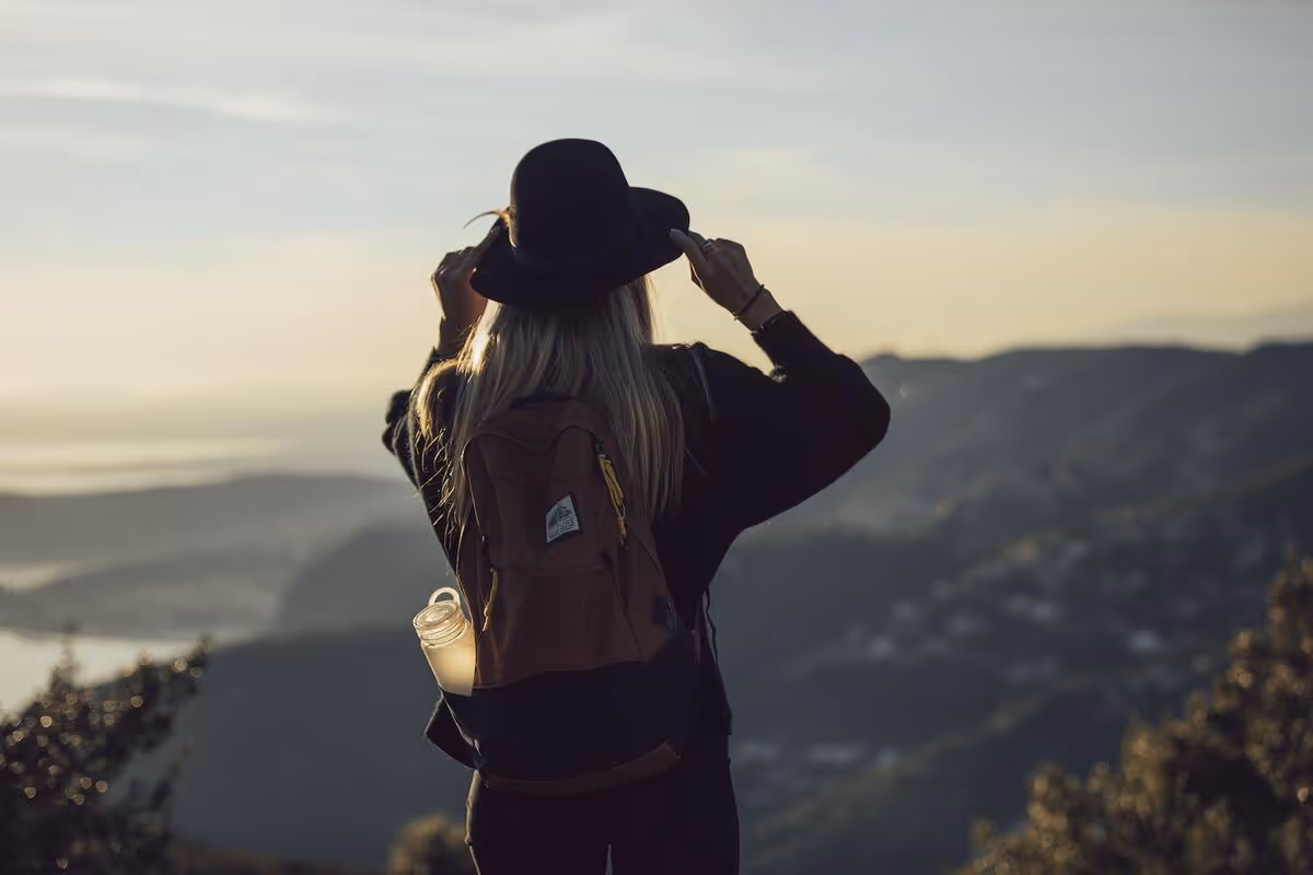 A person standing on a mountain-top with a backpack.