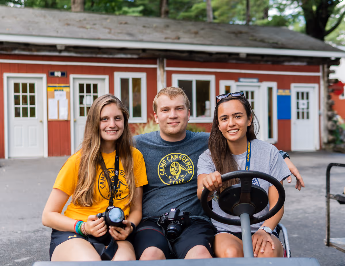 3 camp counselors sat on a golf buggy.