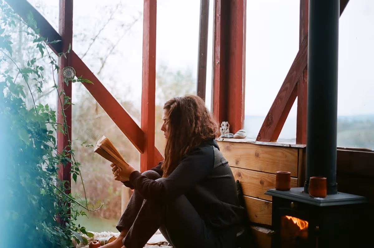 A person reading a book by a window.