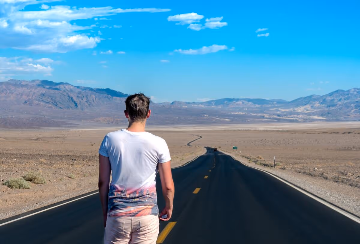 A person standing on a winding road in the desert.