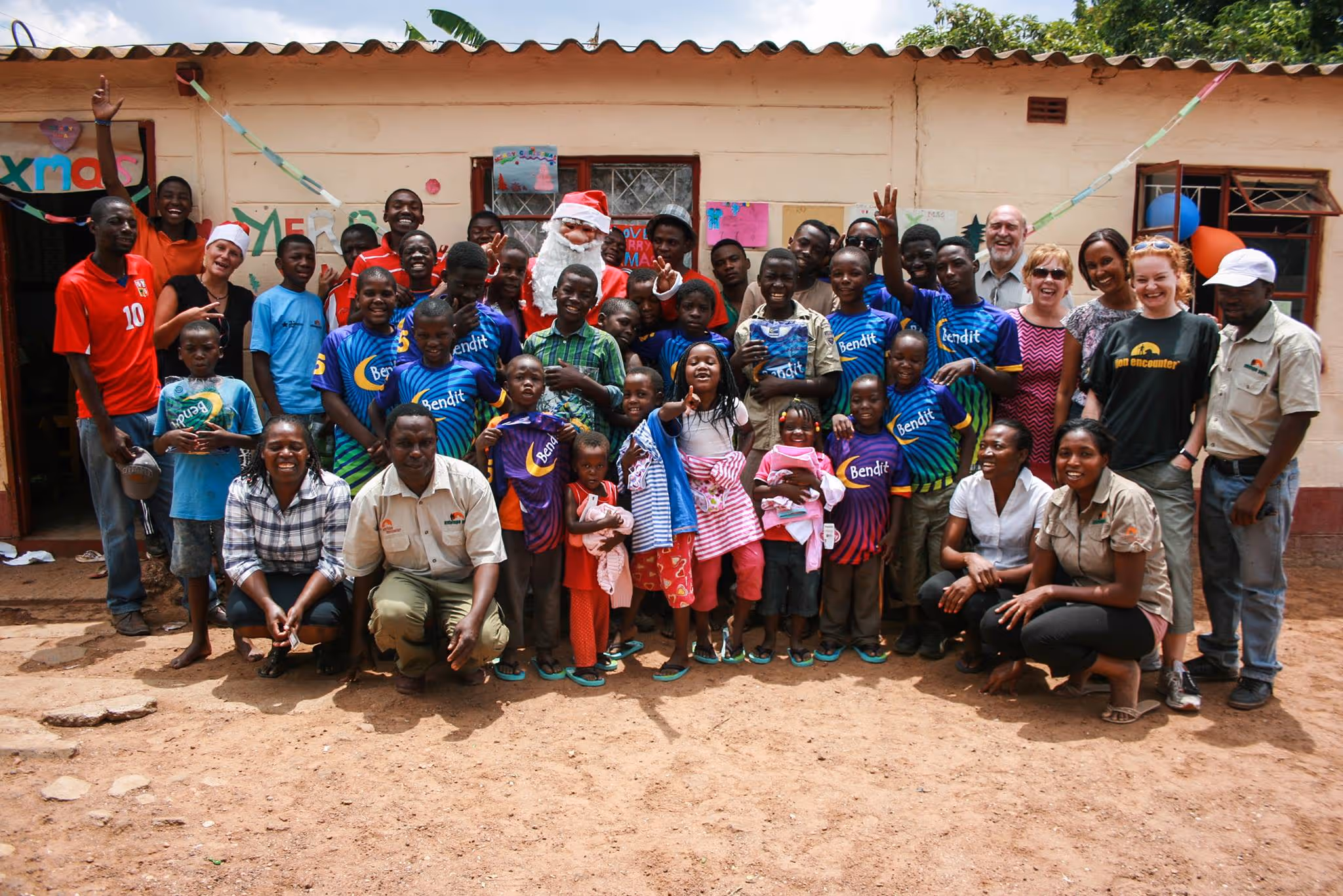 The children, workers, and volunteers smile outside the centre