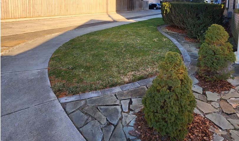 Patio walkway outside the apartments with a patch of grass and some green shrubs