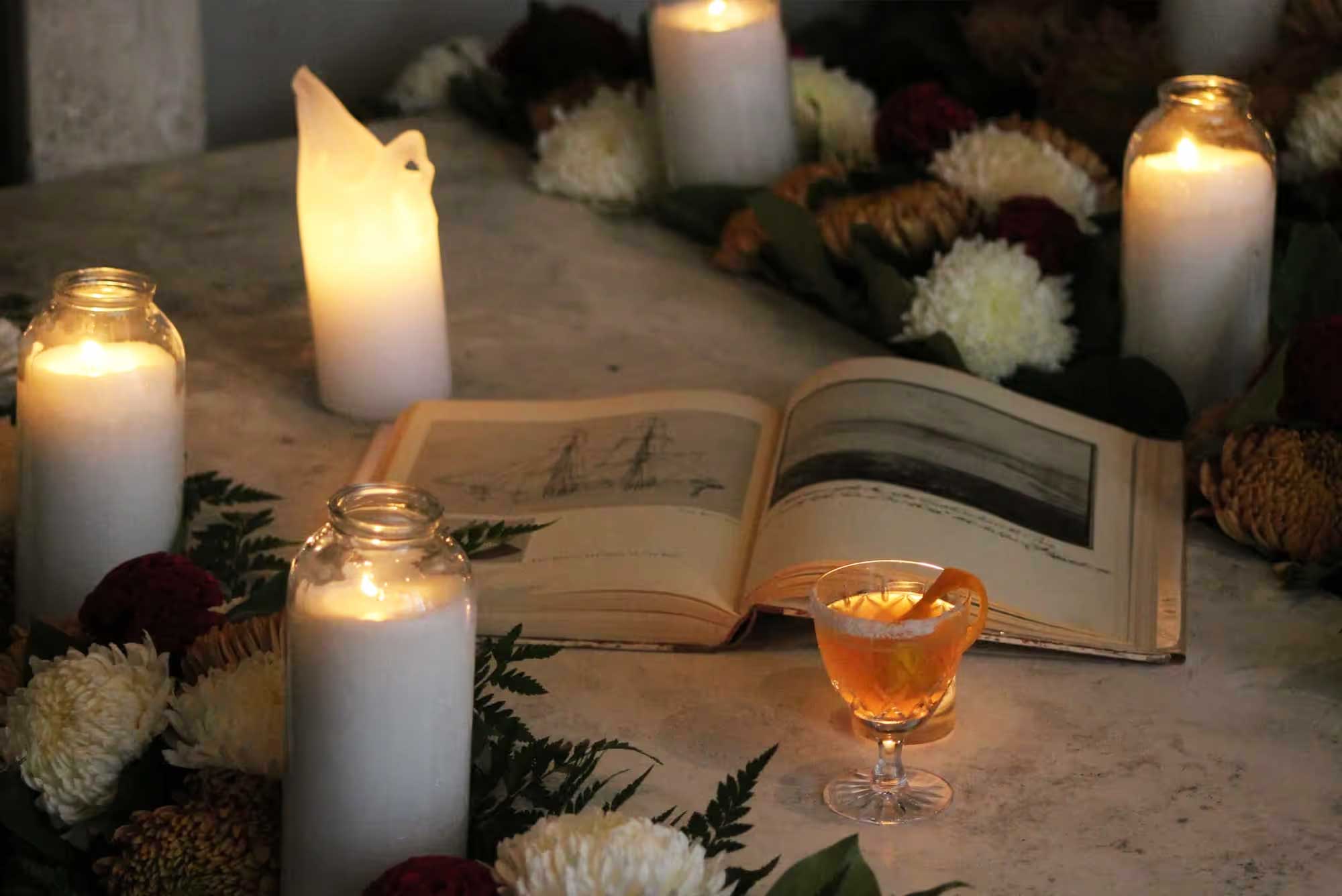 an open book surrounded by candles and flowers