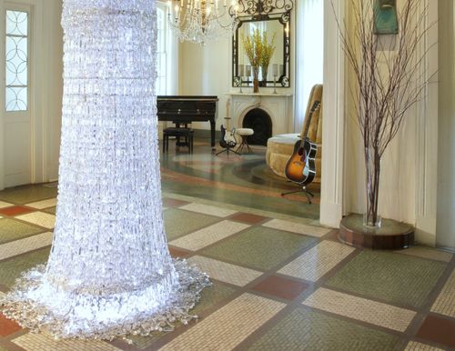 a well lit foyer with a crystal chandelier that hangings from the ceiling all the way to the floor