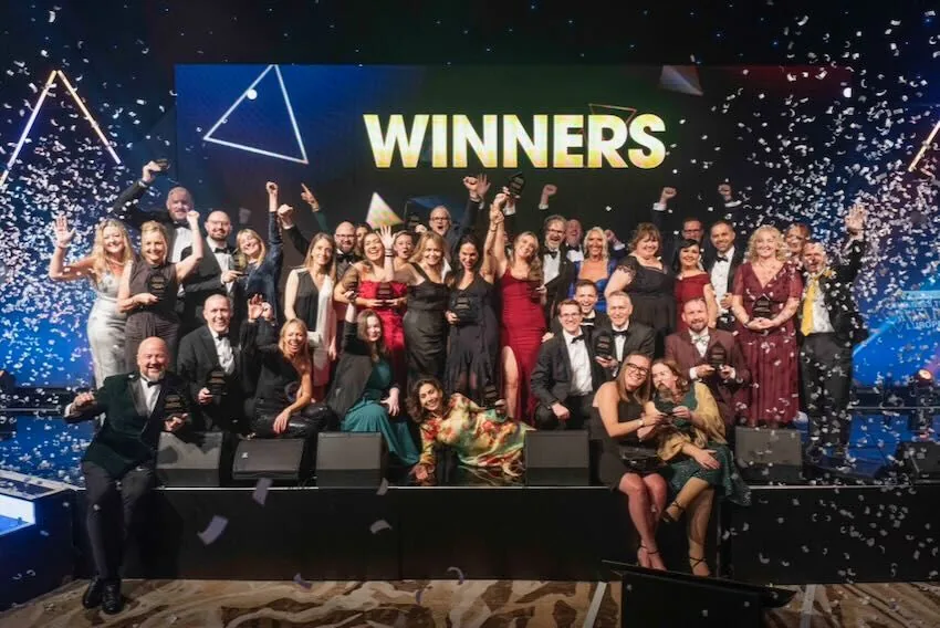 Award winners from across the categories on stage with trophies, confetti falling at an industry awards ceremony
