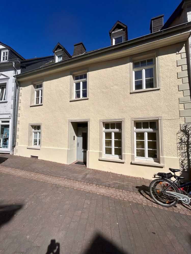 Renoviertes Haus mit neuer Außenfassade auf einer gepflasterten Straße