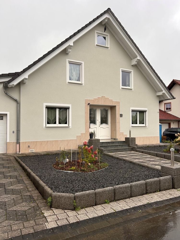 Einfamilienhaus mit Garage mit grüner Fassade und sauberem Vorhof